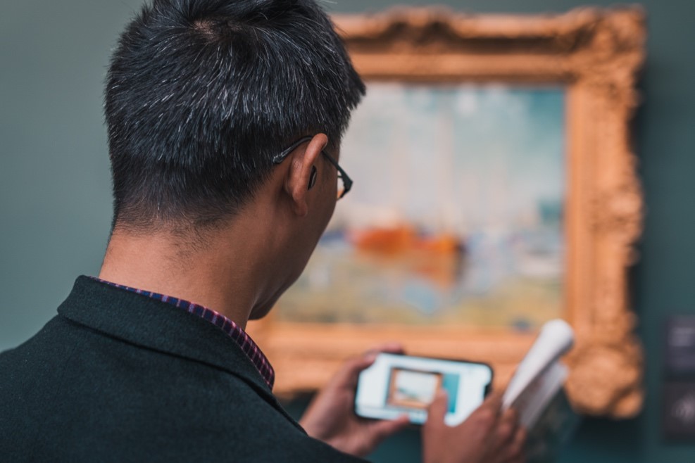 A person capturing an image of a painting with a phone